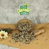 A bowl of birdseed spilling onto a burlap cloth, with a wooden scoop and a flower nearby. Produktbild-Vorschau