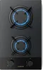 A top-down view of a black gas stovetop with two burners lit with blue flames. Produktbild-Vorschau