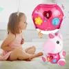A young girl sitting on a bed looking at a pink unicorn toy and a pink interactive ball toy. Anteprima dell’immagine prodotto