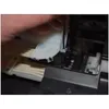 A hand is using a screwdriver to attach a white plastic component to a printer. Produktbild-Vorschau