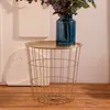 A close-up of a gold wire side table with a blue vase containing flowers on top. Produktbild-Vorschau