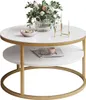 A round coffee table with a gold frame and two white shelves, decorated with a vase of flowers, a bowl of decorative balls, and a candle holder on the top shelf, and a magazine and cup on the lower shelf. Náhled obrázku produktu