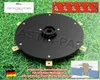 A black circular product with protruding gold-colored metal pieces, set against a green grass background. Several small images and text overlays provide additional information. Náhled obrázku produktu