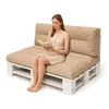 A woman is sitting on a pallet sofa and reading a book. Anteprima dell’immagine prodotto