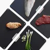 Four black cutting boards are arranged diagonally, each with a different food item on it: sliced chicken, a fish fillet, a raw steak, and chopped green onions. Each cutting board has a small colored dot in one corner (red, blue, green, yellow) and a metall Anteprima dell’immagine prodotto