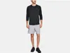A man is standing and modeling a black long-sleeved shirt and gray shorts. Produktbild-Vorschau