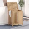 A wooden laundry hamper with its lid open, placed in a room with a plant and artwork in the background. Náhled obrázku produktu