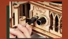 A close-up shot of a person's hand plugging a USB cable into a wooden gramophone model. Podgląd zdjęcia produktu