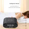 A person's arm is reaching towards a digital alarm clock on a table, with text overlays describing its features. Produktbild-Vorschau
