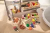 A wooden toy shop with various play food items displayed on shelves and on the floor. Anteprima dell’immagine prodotto