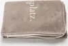 A folded blanket with text on it, lying on a white surface. Produktbild-Vorschau