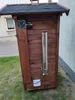 A wooden smoker box with a metal chimney and control panel, placed outdoors on grass next to a building. Anteprima dell’immagine prodotto