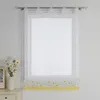 A white sheer curtain with a yellow floral border hangs on a window rod. A vase of white flowers and a framed picture are on a white dresser to the left. Produktbild-Vorschau