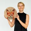 A woman is holding a round wall clock with a watercolor fox design. Produktbild-Vorschau