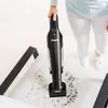 A person using a handheld vacuum cleaner to clean a light-colored fabric surface with dark debris. Produktbild-Vorschau