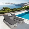 Two rattan sun loungers with dark gray cushions are placed on a patio next to a swimming pool, with a scenic view of the sea and a coastal town in the background. Náhled obrázku produktu
