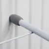 A close-up view of a white laundry rack with a gray rubber stopper on a white wall. Podgląd zdjęcia produktu