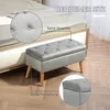 A grey upholstered storage bench with wooden legs is placed next to a bed. Close-up insets highlight the fabric texture and padding. Náhled obrázku produktu
