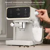 A person is using a white espresso machine to froth milk into a glass mug. Voir les images du produit