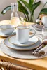 A table setting with plates, a mug, and a carafe of water, suggesting a meal or gathering. Produktbild-Vorschau