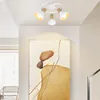 A ceiling light fixture with three adjustable spotlights and a central pendant light is mounted on a white ceiling above a large abstract painting. Voir les images du produit