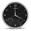 A black analog wall clock with a silver frame, featuring a thermometer and hygrometer. Podgląd zdjęcia produktu