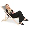 A woman sitting on a foldable deck chair holding a mug. Produktbild-Vorschau
