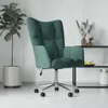 A dark green velvet armchair with a silver base and wheels, placed in a room with a potted plant and a shelf with decorative items. Anteprima dell’immagine prodotto