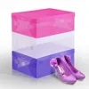 Three stacked shoe boxes in pink, white, and purple, with a pair of purple glitter high heels in front of the bottom box. Anteprima dell’immagine prodotto