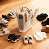 A shoe dryer is shown on a wooden floor surrounded by various footwear and accessories. Produktbild-Vorschau