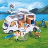 A toy camper set with figures and accessories set up in a grassy area by a lake. Voir les images du produit