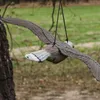 A fake bird of prey decoy is hanging from a string in front of a tree and blurred green background. Náhled obrázku produktu