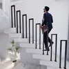 A man in a suit walks up a modern staircase with black U-shaped railings. Náhľad obrázku produktu