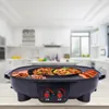A 2-in-1 electric grill and hot pot is shown on a wooden table in a blurred kitchen setting. Produktbild-Vorschau