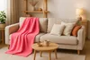 A cozy living room scene with a sofa, throw blanket, pillows, and a coffee table. Produktbild-Vorschau