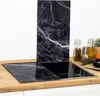 A kitchen counter with a glass stovetop cover and a backsplash panel, both with a black marble pattern. Náhled obrázku produktu