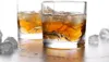 Two glasses of whiskey with ice cubes on a reflective surface. Produktbild-Vorschau