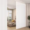 A bedroom divided by a white accordion-style curtain, with a bed visible on one side. Voir les images du produit