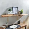 A wooden shelf with decorative items above a desk with a notebook and pens. Náhled obrázku produktu