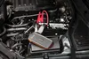 A car battery and jump starter kit are shown in an engine bay. Náhled obrázku produktu