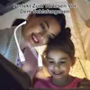A mother and daughter are reading a book together in a tent, illuminated by neck reading lights. Produktbild-Vorschau