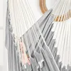A woman relaxing in a gray hammock chair indoors, with a mirror in the background. Produktbild-Vorschau