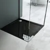 A close-up view of a modern black shower tray with a textured surface and a silver drain cover, set within a contemporary bathroom. Produktbild-Vorschau