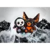 Two Halloween-themed plush toys, a grim reaper and a bat-bear, sit on a bed of fake cobwebs and black shredded paper. Produktbild-Vorschau