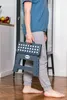 A person holding a folded gray step stool indoors. Náhled obrázku produktu