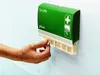 A hand is taking a plaster strip from a dispenser mounted on a wall. Anteprima dell’immagine prodotto