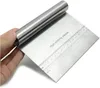 A hand holding a stainless steel bench scraper with a ruler marking. Produktbild-Vorschau