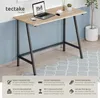 A desk with a laptop, phone, and coffee cup on it, set against a blue and white wall with a plant in a pot. Náhled obrázku produktu