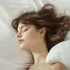 A woman sleeping peacefully with earbuds in her ears. Produktbild-Vorschau