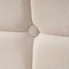 A close-up view of tufted beige fabric with a button. Produktbild-Vorschau